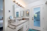 In the master bathroom there is large vanity and a door out to the back yard. 